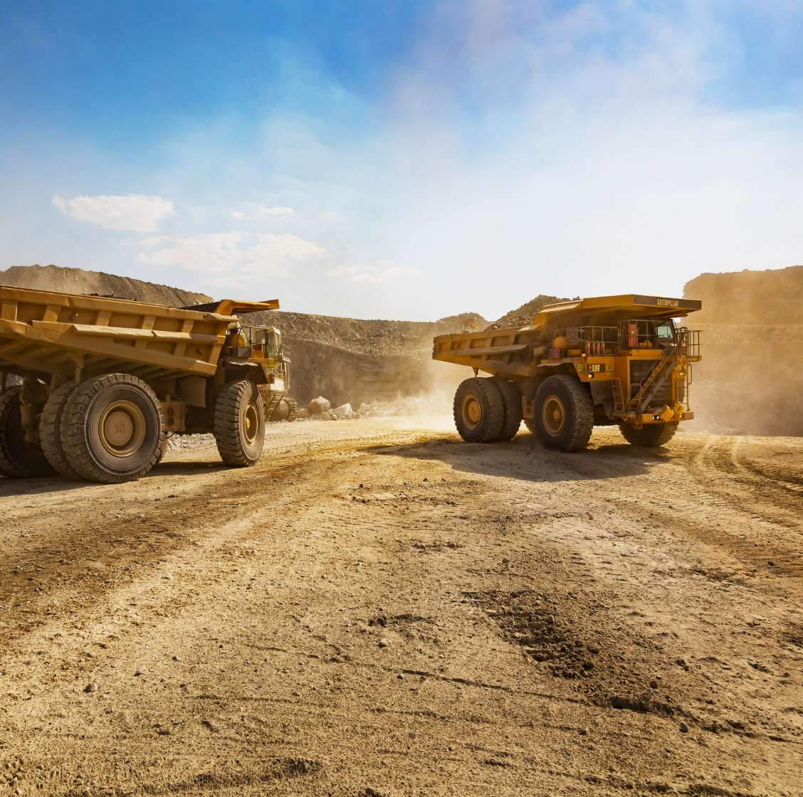 two huge trucks at a desert mining site