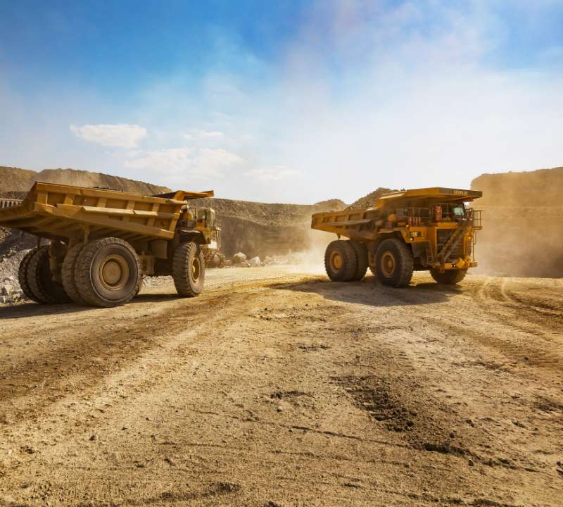 two huge trucks at a desert mining site