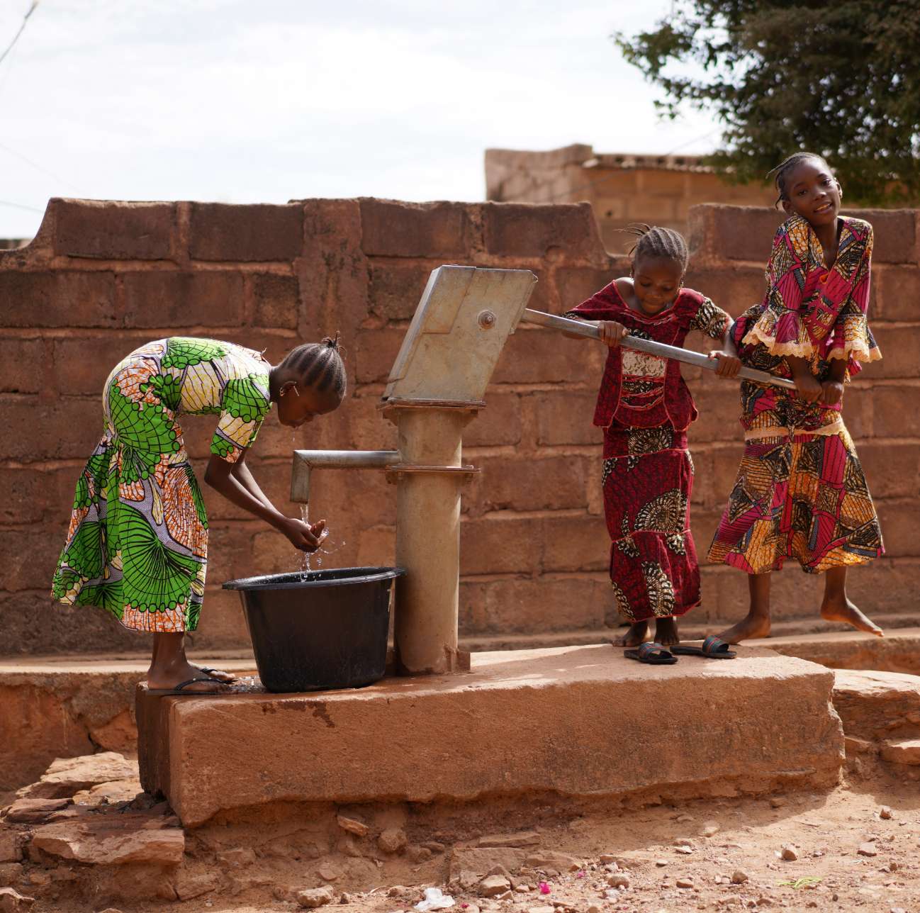 three women around a potable water tap